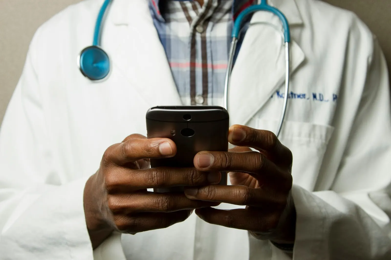 Betriebsarzt mit Stethoskop und Smartphone