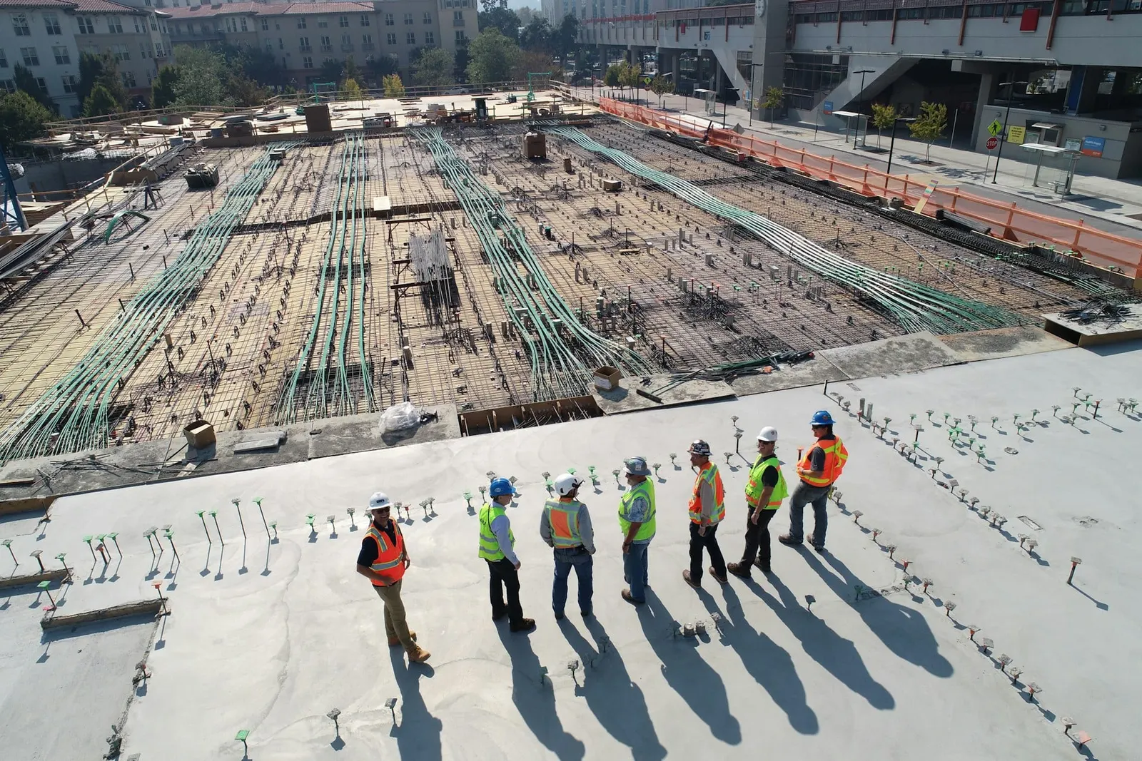 Baustelle von oben: Bauteam mit Warnwesten auf der Bodenplatte